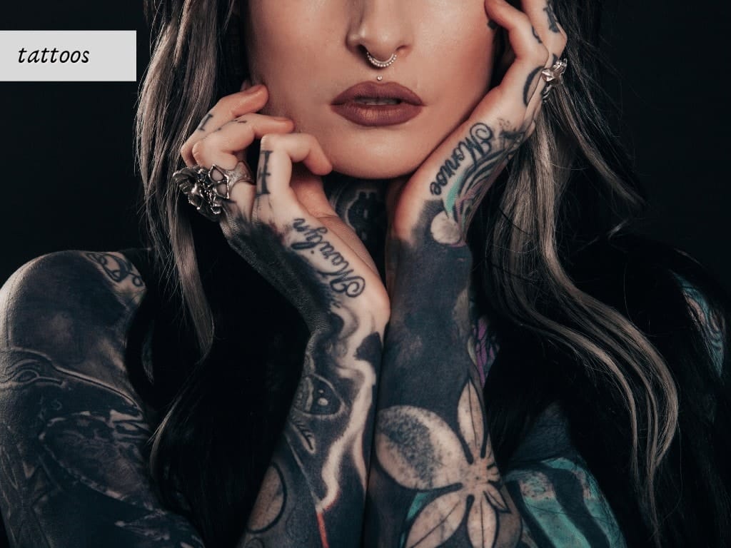 A woman with tattoos posing on a black background.