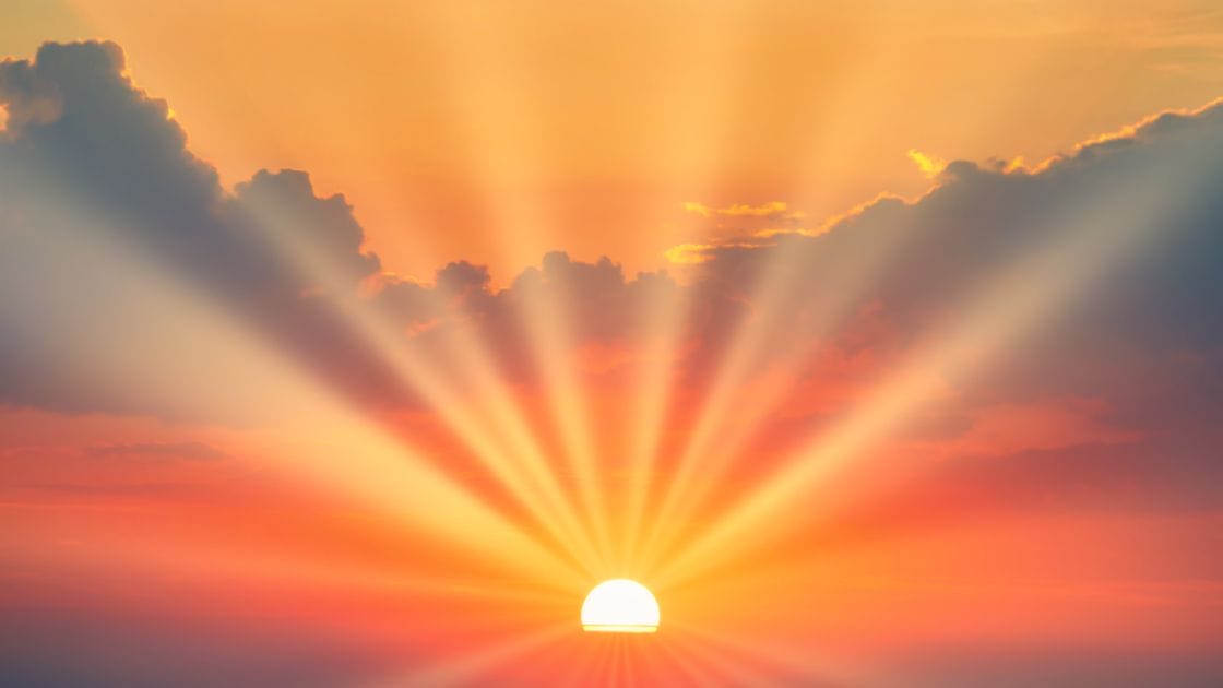 Sunrise over the ocean with sun rays.