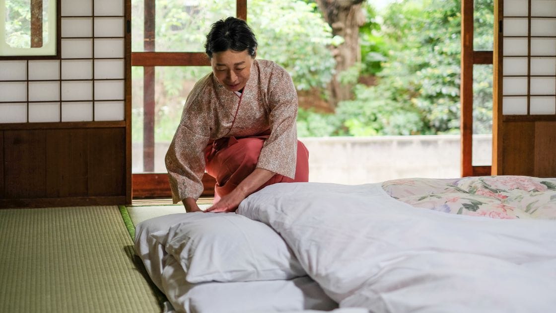 A woman in a kimono is making a bed.
