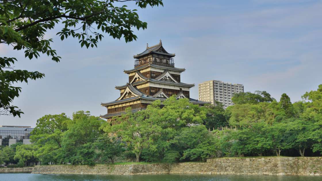 An old japanese tower sits on top of a body of water.