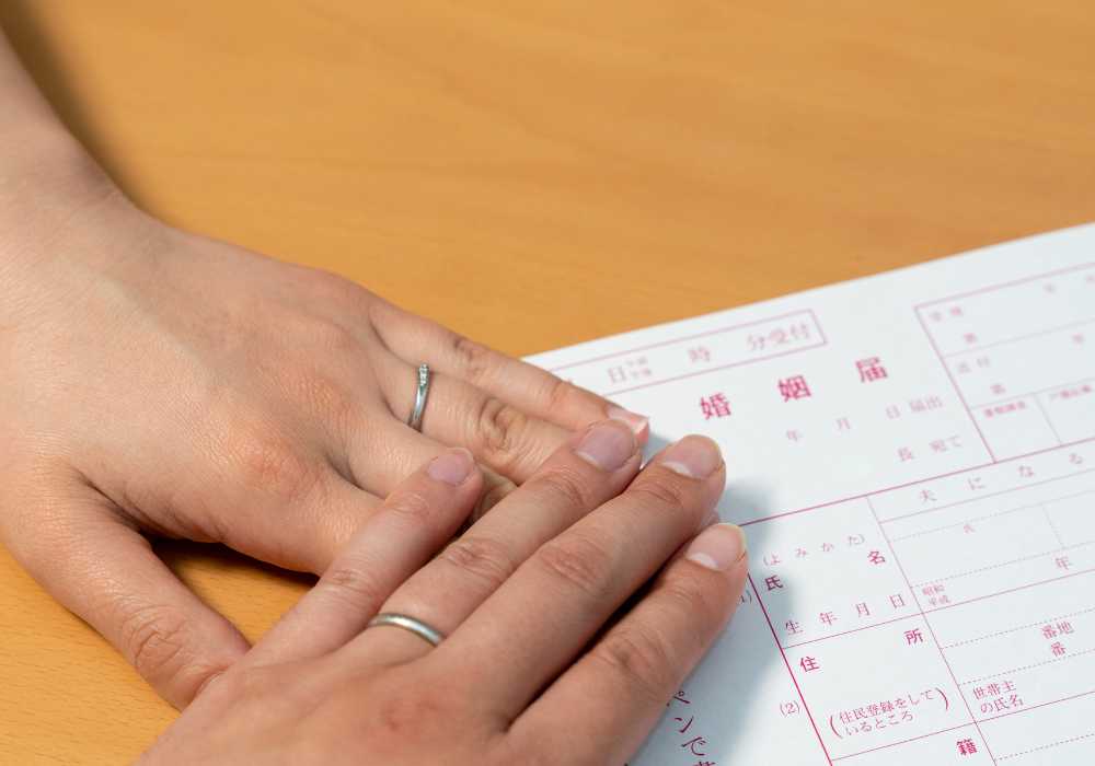 A woman holding a wedding ring on a piece of paper.