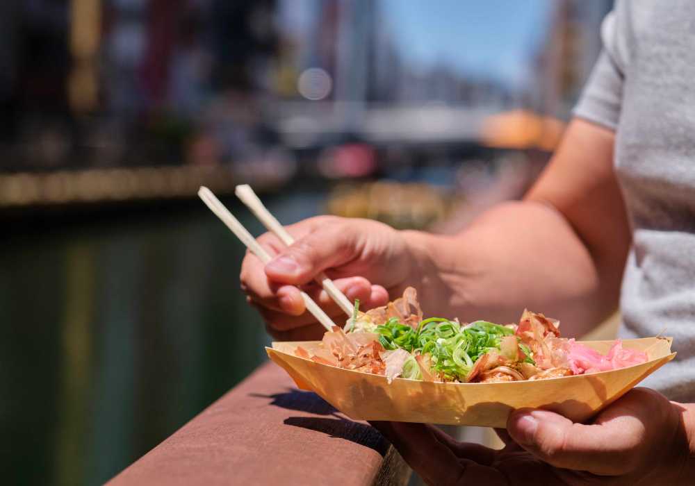 A man is holding a bowl of food with chopsticks.