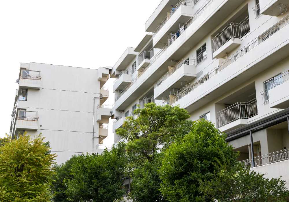Modern apartment building with balconies, surrounded by greenery.