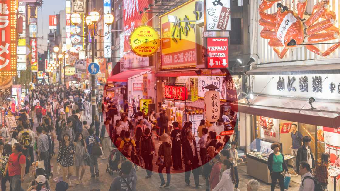 Crowded street in japan at night, lined with illuminated signs and bustling with pedestrians.