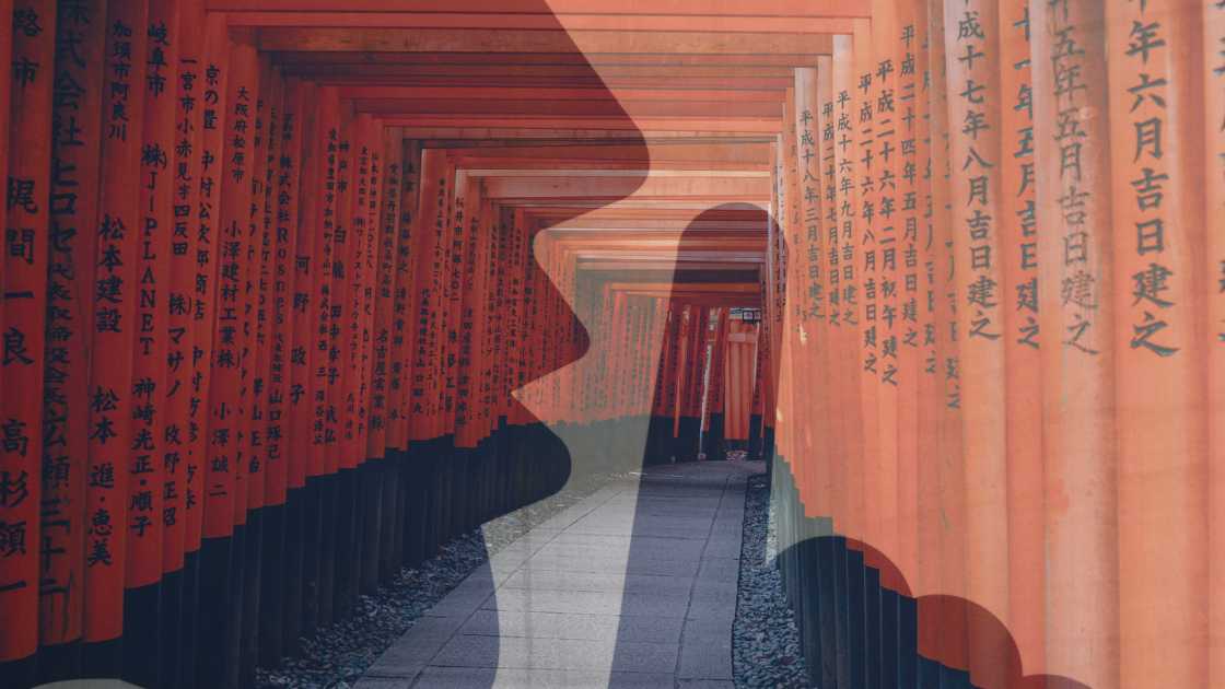 Curved pathway lined with closely set red torii gates featuring inscriptions, exemplifying the serene atmosphere Why Japan Is So Quiet, in Fushimi Inari Shrine, Kyoto.