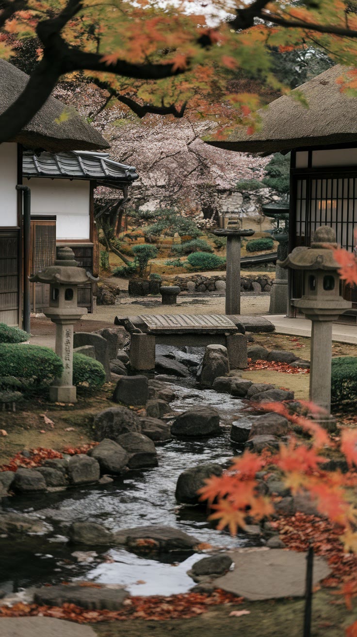 Japanese garden with a stone lantern, small bridge over a stream, and autumn foliage. Traditional buildings and manicured shrubs are in the background.