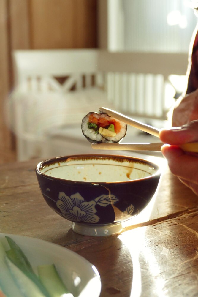 A Japanese meal featuring grilled salmon in broth, a bowl of white rice, pickles, and another piece of grilled salmon on a separate plate.