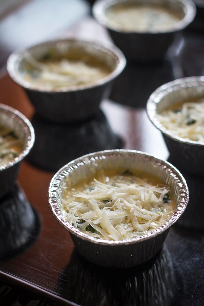 A bowl of rice soup with sliced mushrooms, seaweed, and chopped green onions on top, placed on a wooden trivet on a table.