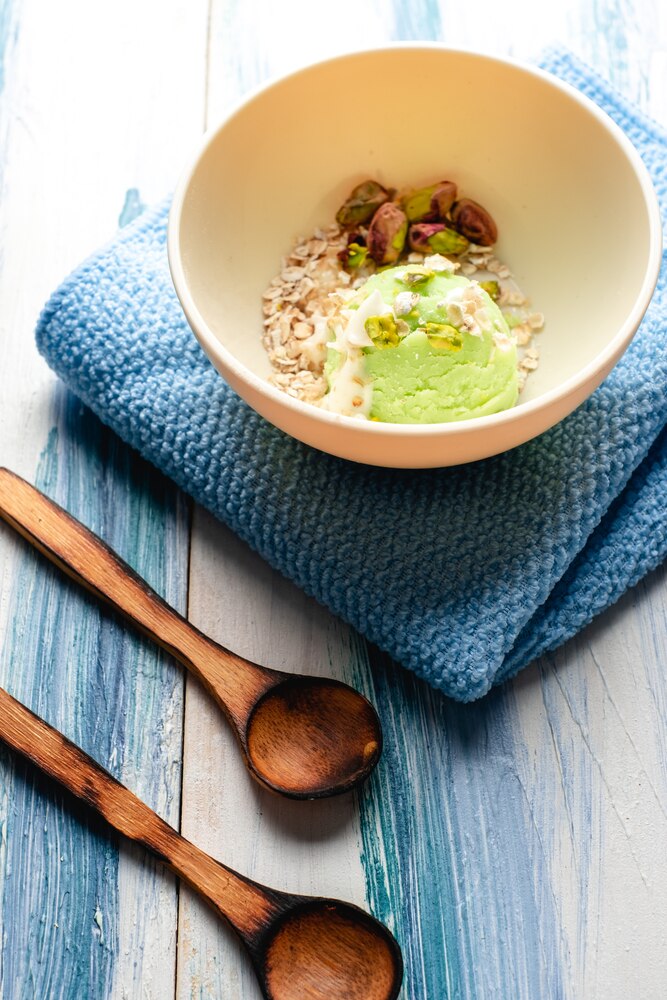 A bowl of miso soup with tofu and green onions is surrounded by small bowls of udon noodles, shiitake mushrooms, broth, lettuce, carrots, chicken, and seaweed.