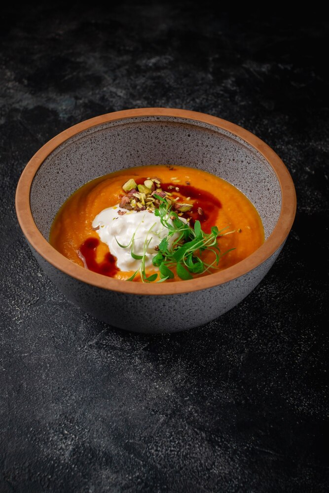 A bowl of clear soup with shiitake mushrooms, chives, and noodles, served on a wooden tray with a slice of bread.