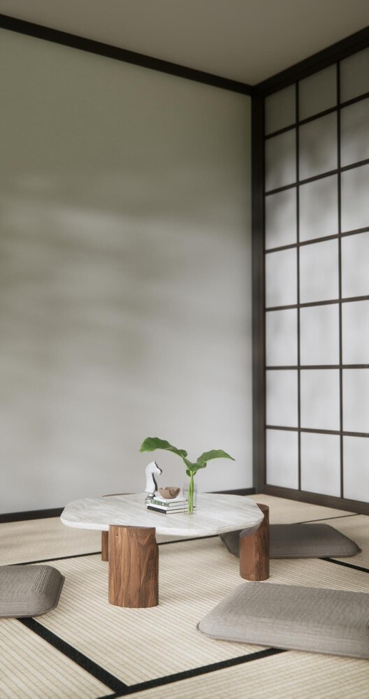 A minimalist room with tatami mats, a low wooden table, and a vase with a single branch, set against shoji screen doors and beige walls.