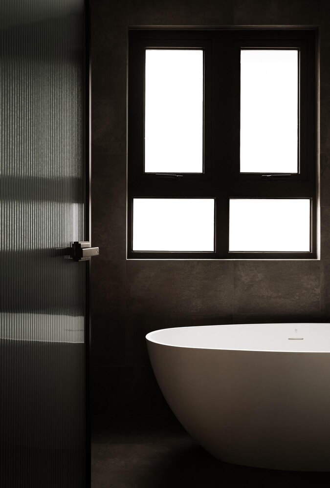 A spray bottle labeled "gentle clean," a wooden brush with bristles, and folded towels are placed on a marble bathroom ledge near a glass shower door.