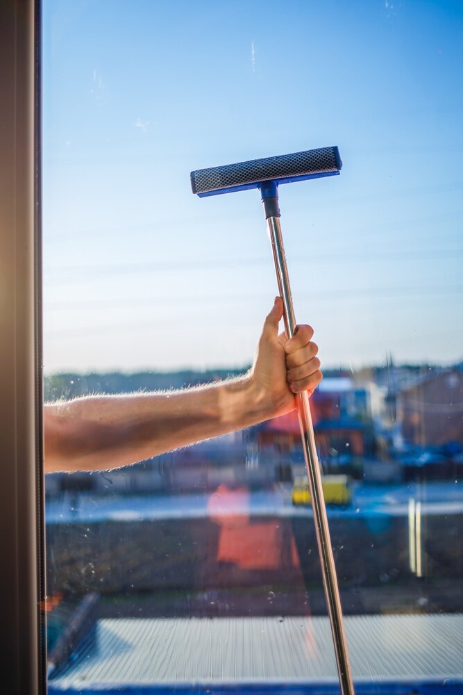 A person using a squeegee to clean a glass shower door, demonstrating the Japanese cleaning tip.
